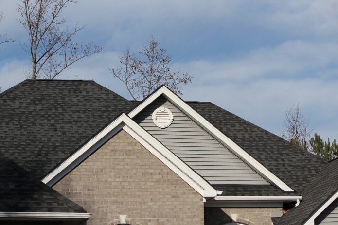 This is the image of about the top third of a home. The home has a roof with many distinct peaks. The image is used to support our South Shore roof replacement services business' blog post about "Roofing Problem Signs To Look For When Buying a Home"